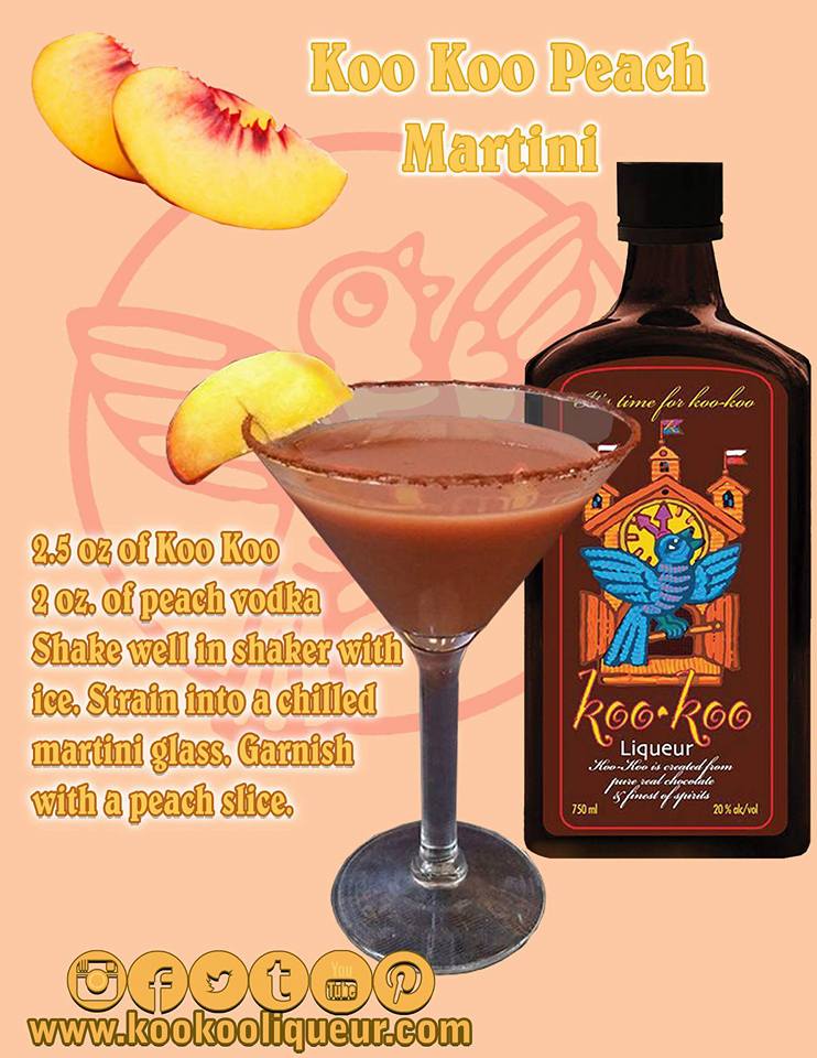 A chilled martini glass filled with a golden Koo Koo Peach Martini, garnished with a fresh peach slice on the rim, surrounded by peach halves and chocolate squares.