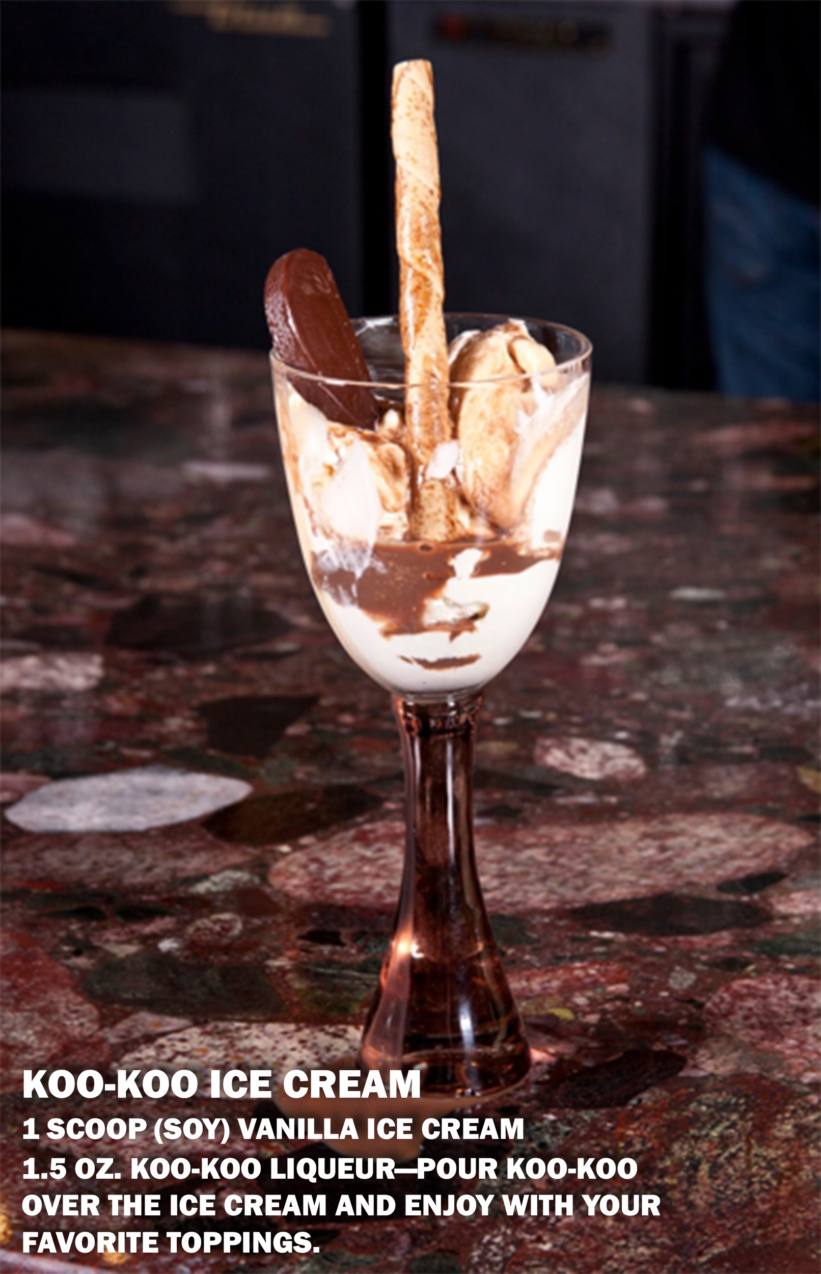 A bowl of vanilla ice cream drizzled with Koo Koo Liqueur, topped with chocolate shavings, and ready to be enjoyed with a spoon.